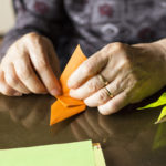 Hands of senior lady folding Origami paper