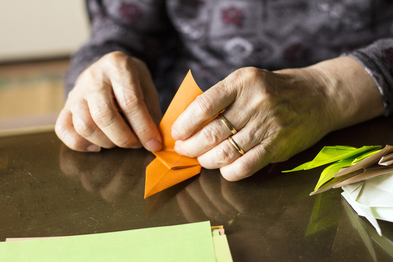 Hands of senior lady folding Origami paper