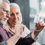 portrait of senior couple looking at pill bottle in hand