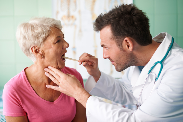 Doctor checking throat of senior woman