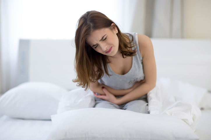woman sitting on the bed with pain