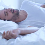 Man snoring because of apnea lying in the bed
