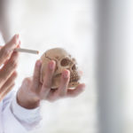 The medical doctor with stethoscope hold skull in one hand and cigarette in one hand in the concept of the danger of smoking and stop smoking, Closeup and soft tone