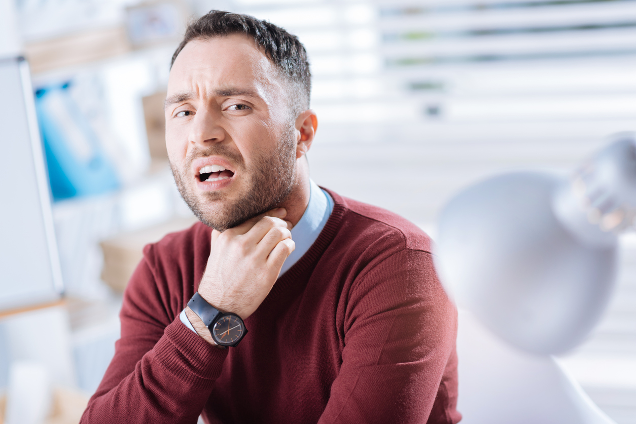 Emotional worker touching his neck and having a sore throat