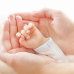 Mother's hands holding newborn baby