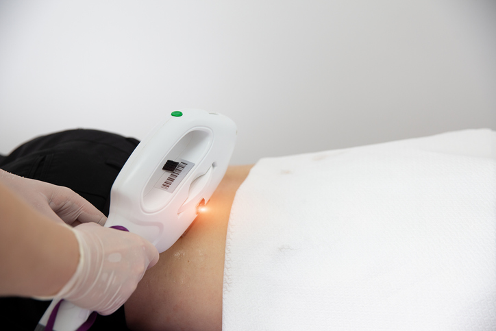 Young Man Receiving Laser Epilation Treatment From Beautician At Beauty Center