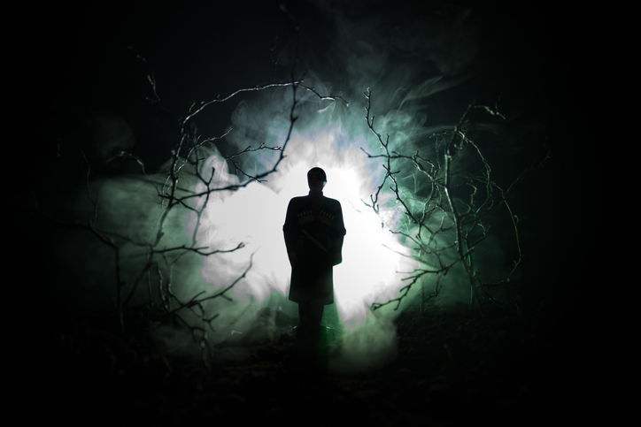 strange silhouette in a dark spooky forest at night, mystical landscape surreal lights with creepy man. Toned