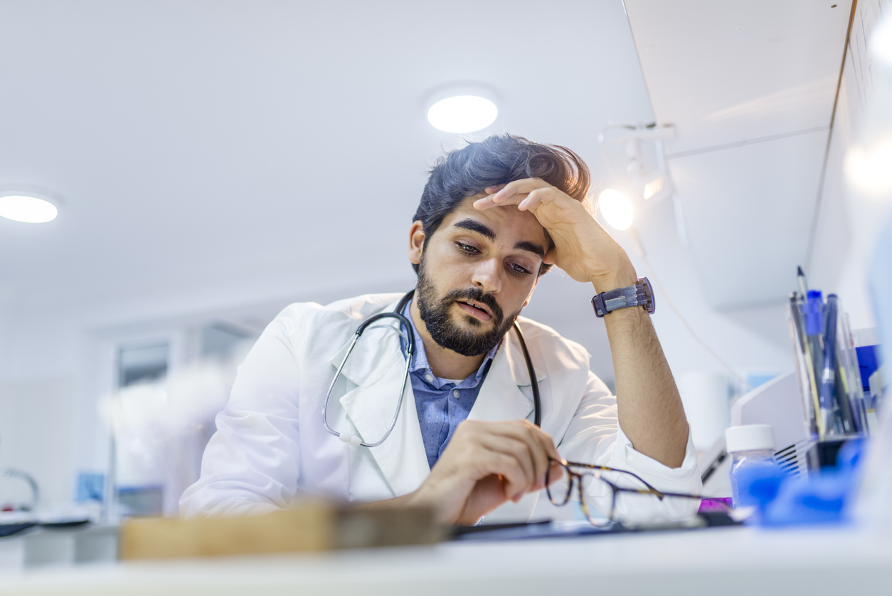 Stressed male doctor sat at his desk