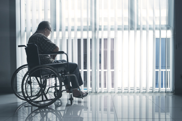 Sad elderly man sits in the wheelchair