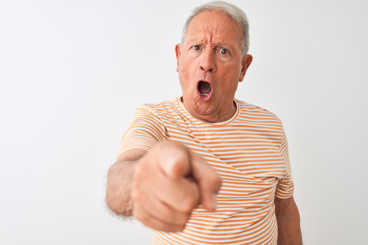 Senior grey-haired man wearing striped t-shirt standing over isolated white background pointing displeased and frustrated to the camera, angry and furious with you