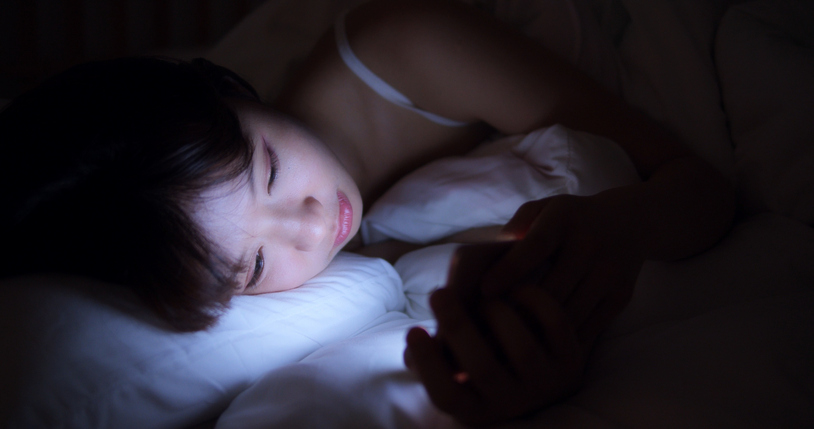 Woman Using Cellphone In Bed At Night
