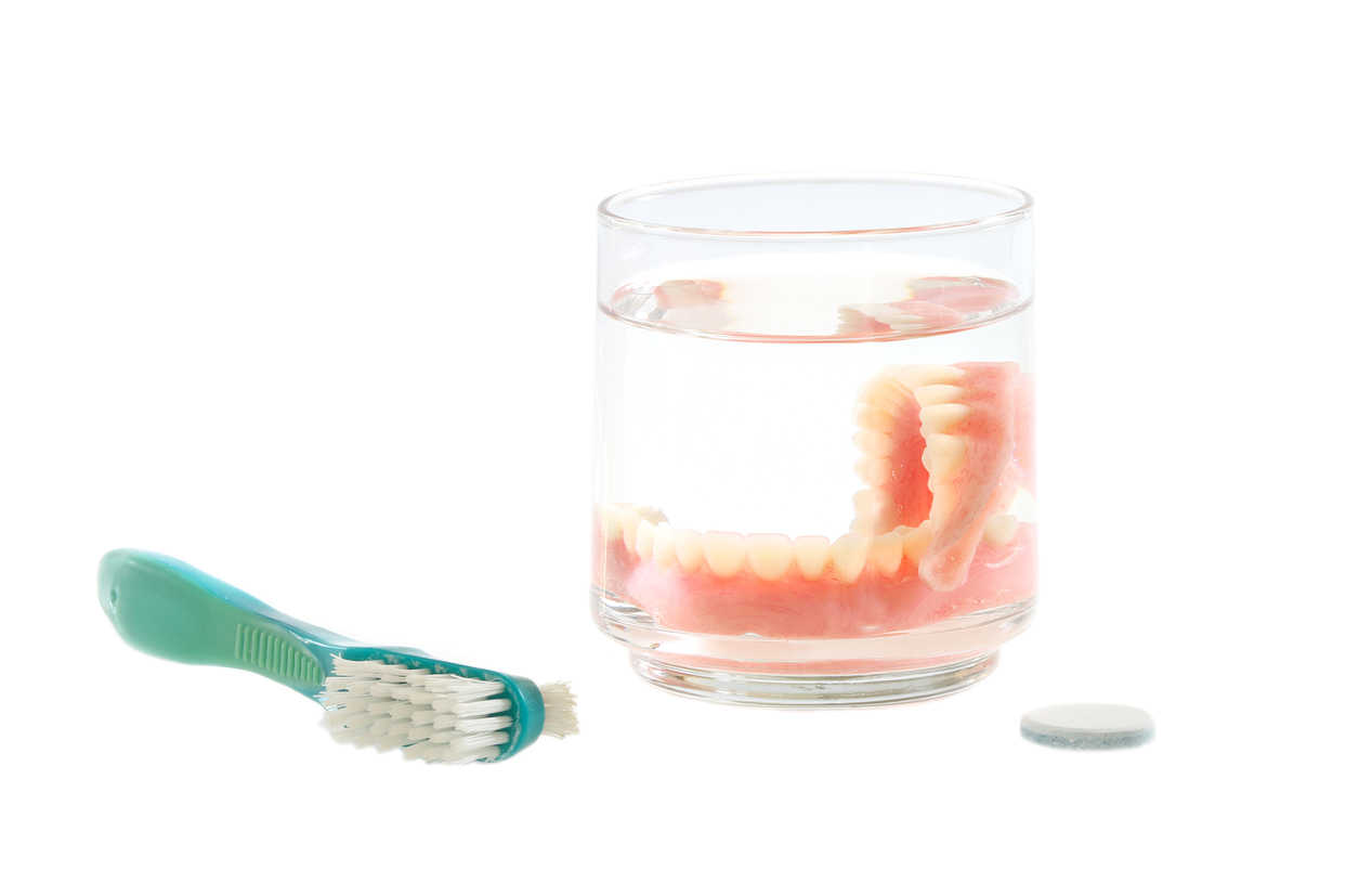 False Teeth Isolated on White With Brush and Cleaner