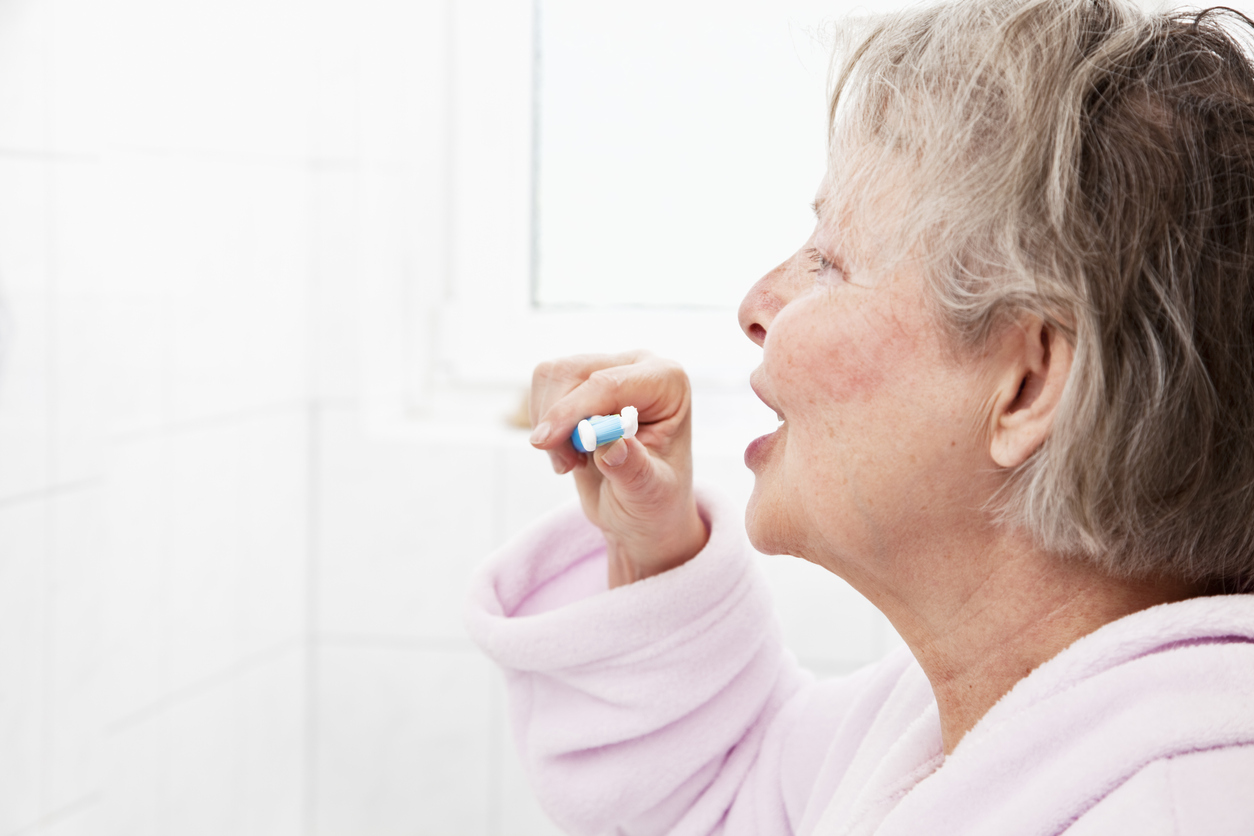 profile of senior woman brushing teeth