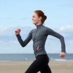 Smiling woman jogging at the sea side