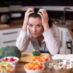 A frustrated woman looking out at salad bowls in her kitchen