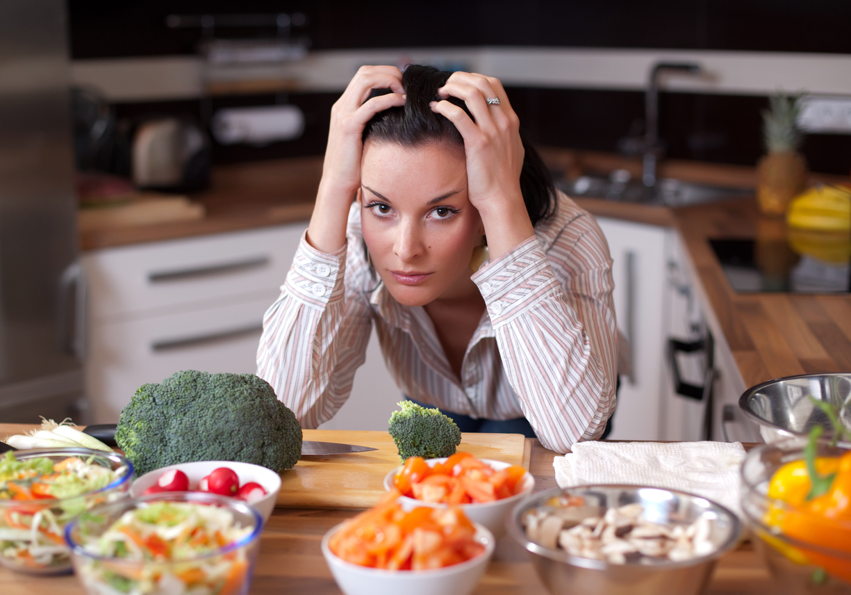 A frustrated woman looking out at salad bowls in her kitchen