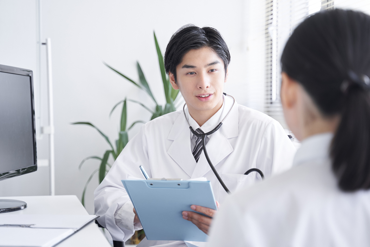 A Japanese male doctor examining a female office worker